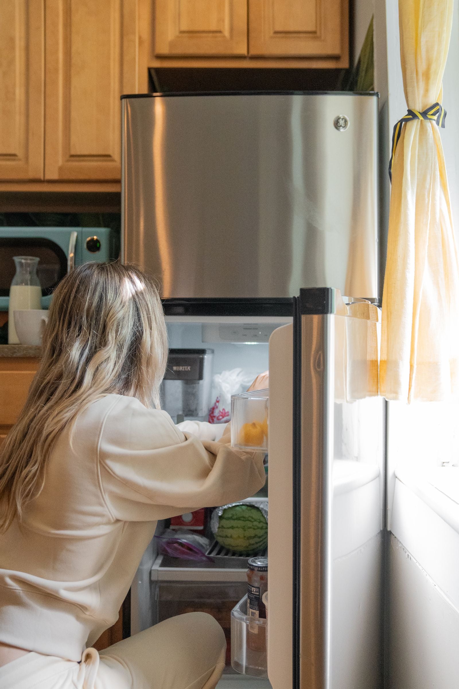 Woman organizing groceries in a bright home kitchen